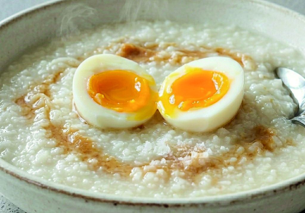 A bowl of creamy rice congee topped with a halved soft-boiled egg.