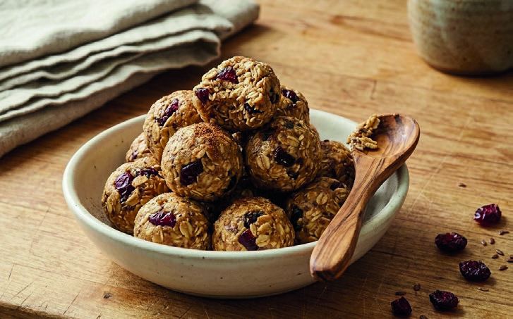 A bowl of peanut butter and oat energy bites with a wooden spoon.