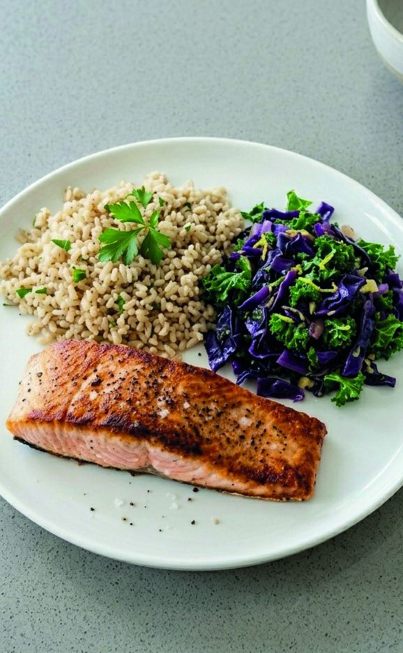 A plate of seared salmon with brown rice and a red cabbage and kale slaw.